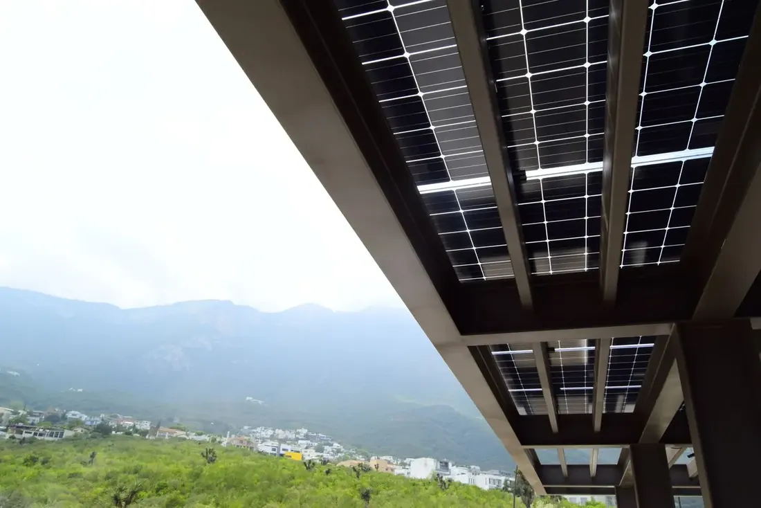 Vista bajo la pérgola solar, plafón de paneles con la montaña al fondo